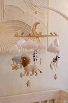 a crib mobile with animals and stars hanging from it's sides in a nursery room