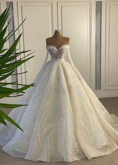 a wedding dress on display in front of a plant