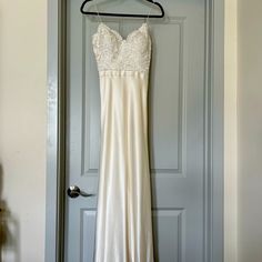 a wedding dress hanging on a hanger in front of a door with a blue door