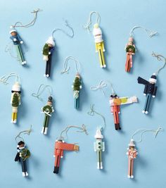 several ornaments made to look like people hanging from strings on a blue surface with white string