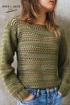 a woman standing in front of a wall with her hands on her hips wearing a green sweater