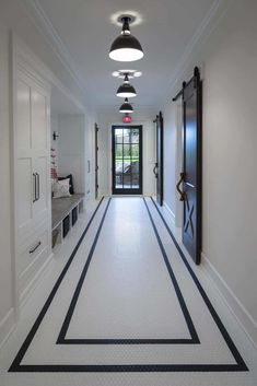 a long hallway with black and white striped flooring next to an open front door