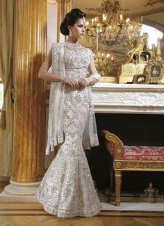 a woman standing in front of a fireplace wearing a white dress with silver sequins