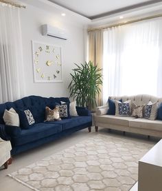 a living room with two couches and a rug in front of a window that has curtains on it