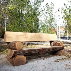 a wooden bench made out of logs sitting in the middle of a park