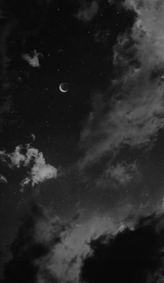 black and white photograph of the moon in the sky with clouds around it at night