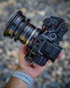 a camera being held up in the air with its lens attached to it's body