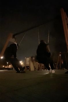 two people on swings in the dark at night