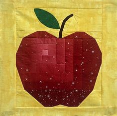 an apple quilted on top of a yellow piece of cloth with green leaves and stars