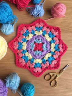 crocheted grannys are arranged on a table with yarn, scissors and balls of yarn