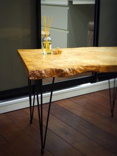 a wooden table with hairpin legs and a vase filled with reeds on it