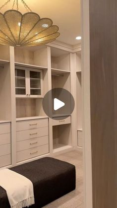 an empty room with white cabinets and black bench in the center, and a chandelier hanging from the ceiling