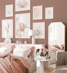 a bedroom with pink walls and pictures on the wall above the bed, along with a white chair