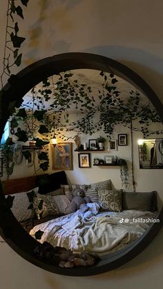 a round mirror hanging on the wall above a bed with pillows and blankets in front of it