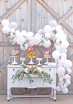 a table with white balloons and flowers on it, next to a wooden wall that says instagram