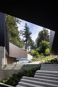 stairs lead up to the upper level of this modern house with trees in the background