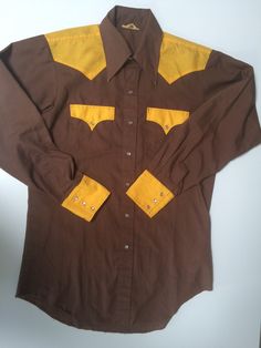 Vintage Western Men's color block shirt-chocolate brown w/nice bright golden yellow. Size 15 1/2 neck x 34" sleeve. Would say this is a size Medium, but slightly fitted, very flattering Permanent press with mother of pearl snap buttons. Triple snap cuffs. Other than a little grin through at the collar tips(see close up),and slight fraying at shirt tail  this is in excellent condition (fixable) Payment - All major credit cards and Paypal  Shipping - If you don't find your country listed as a shipping option, please send me an email and I will do my best to find shipping costs for your country. Most packages will be sent by USPS regular mail and do not automatically come with insurance. If you want your item insured please advise me before ordering.  Refunds and Exchanges - Sorry, but not in Fitted Cotton Shirt With Color Block, Fitted Cotton Color Block Shirt, Fitted Yellow Shirt For Fall, Yellow Fitted Shirt For Fall, Brown Fitted Shirt For Fall, Fitted Brown Shirt For Fall, Fitted Brown Collared Shirt, Retro Brown Long Sleeve Shirt, Fitted Collared Brown Shirt