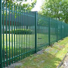 a green metal fence next to a grassy field