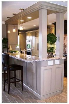 a kitchen with an island in the middle and two bar stools at the end