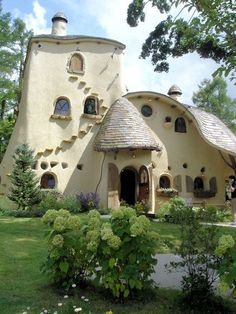 an unusual looking house in the middle of a park with lots of trees and flowers