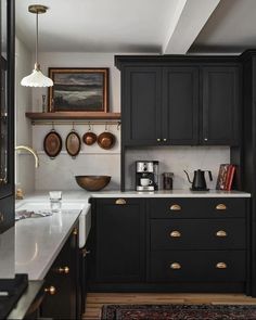 a kitchen with black cabinets, white counter tops and gold pulls on the handles is shown