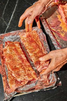 two hands are holding some meat on tin foil and another hand is reaching for it