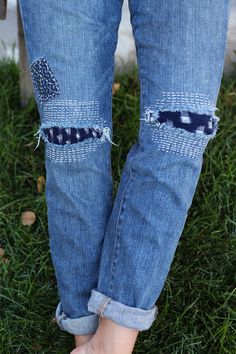 a person standing in the grass with their feet crossed and wearing jeans that have holes on them