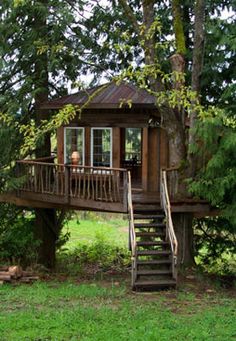 a tree house in the woods with stairs leading up to it's second floor