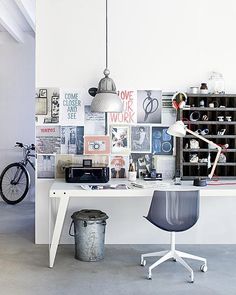 a white desk topped with a laptop computer next to a chair and table covered in pictures