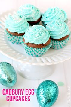 cupcakes with blue icing on a white cake plate