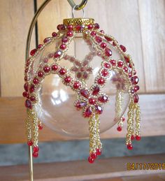 a glass ornament with beads hanging from it's side on a stand