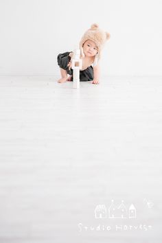 a baby is sitting on the floor playing with a white pole and wearing a hat