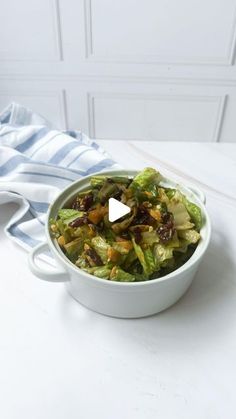 a white bowl filled with lettuce and raisins on top of a table