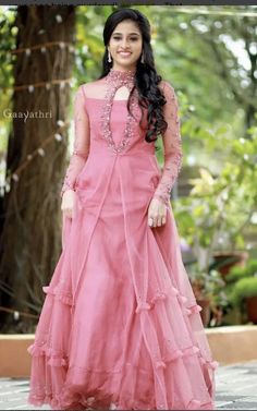 a woman in a long pink dress posing for the camera with her hands on her hips