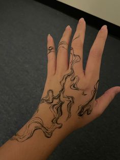 a woman's hand with black ink on it and wavy lines in the middle