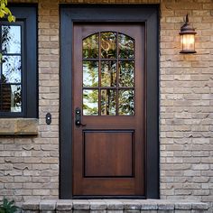 the front door to a house with two windows and a brick step leading up to it