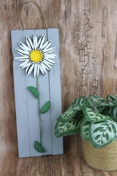 a white flower sitting on top of a wooden board next to a potted plant