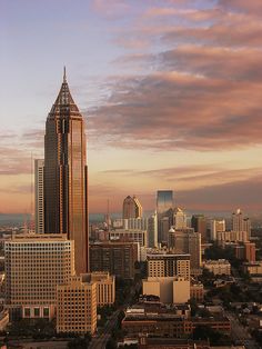 an aerial view of a city with skyscrapers in the foreground and clouds in the background