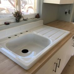 a white sink sitting under a window next to a wooden counter top in a kitchen