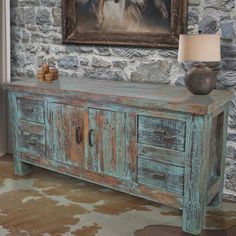 an old wooden sideboard with two drawers in front of a painting on the wall