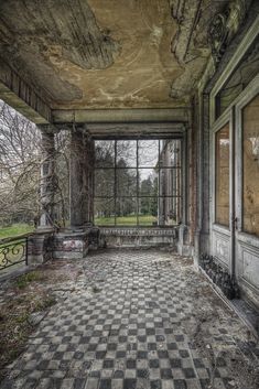 an abandoned building with windows and checkered flooring in the foreground, looking out onto a grassy field