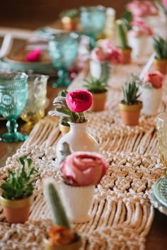 the table is set with pink flowers in vases and succulents on it