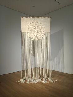 a large white sculpture with fringes hanging from it's sides in a room