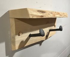 a wooden shelf with two hooks on it and some screws attached to the wall