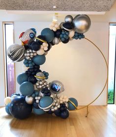 a large balloon arch in the middle of a room with balloons all over it and an object on top