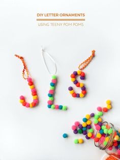 colorful beads spelling out the word joy on a white surface next to an empty jar