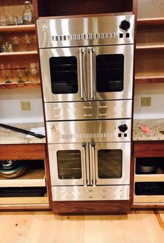 two double ovens are stacked on top of each other in a kitchen with open shelving