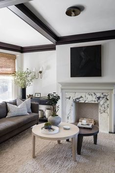 a living room with two couches and a table in front of a fire place