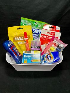 a white basket filled with lots of different items on top of a table next to a black background