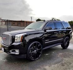 a black suv parked in front of a fence